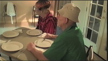 Movie still from “Trash Humpers” (2009), directed by Harmony Korine – Two people sitting at a table with plates on it; Medium shot, High angle