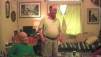 Movie still from “Trash Humpers” (2009), directed by Harmony Korine – An older man standing in a living room with an older woman; Medium shot, Over the shoulder angle