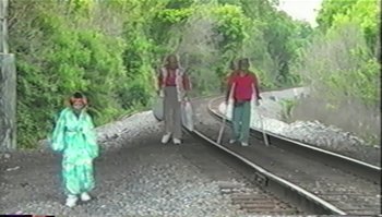 Movie still from “Trash Humpers” (2009), directed by Harmony Korine – A group of people standing next to each other on train tracks; Wide shot, High angle