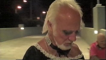 Movie still from “Trash Humpers” (2009), directed by Harmony Korine – An old man with white hair wearing a black dress; Close Up shot, High angle