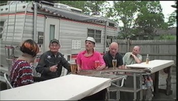 Movie still from “Trash Humpers” (2009), directed by Harmony Korine – A group of men sitting at a table drinking beer; Wide shot, High angle
