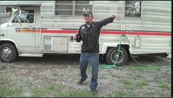 Movie still from “Trash Humpers” (2009), directed by Harmony Korine – A man holding a camera in front of an rv; Wide shot, Low angle