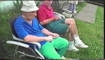 Movie still from “Trash Humpers” (2009), directed by Harmony Korine – Two older men sitting in lawn chairs on grass; Medium shot, High angle