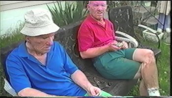 Movie still from “Trash Humpers” (2009), directed by Harmony Korine – Two older people sitting on a bench looking at their cell phones; Medium shot, High angle