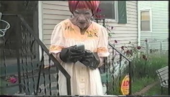 Movie still from “Trash Humpers” (2009), directed by Harmony Korine – An older woman wearing gloves standing on a porch; Extreme Close Up shot, Low angle