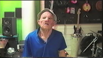 Movie still from “Trash Humpers” (2009), directed by Harmony Korine – An old man wearing a hat is standing in a room; Medium shot, High angle