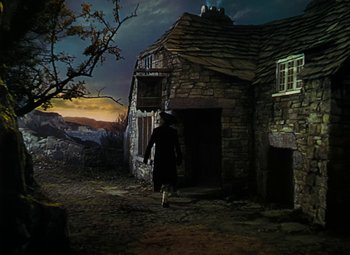 Movie still from “Treasure Island” (1950), directed by Byron Haskin – A person dressed as a witch walking outside a house; Extreme Wide shot, High angle