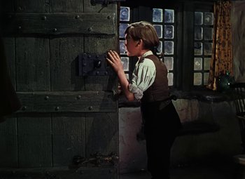 Movie still from “Treasure Island” (1950), directed by Byron Haskin – A young man in a suit and tie looking at a wall; Medium shot, High angle