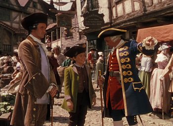 Movie still from “Treasure Island” (1950), directed by Byron Haskin – Two men in period costumes talking to a young boy in medieval garb; Medium shot, High angle