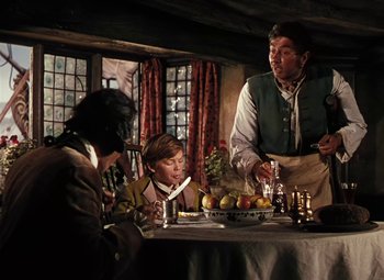 Movie still from “Treasure Island” (1950), directed by Byron Haskin – A group of people sitting at a table with food on it; Medium shot, Over the shoulder angle