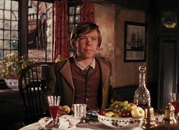 Movie still from “Treasure Island” (1950), directed by Byron Haskin – A woman sitting at a table with a bowl of fruit; Medium shot, High angle