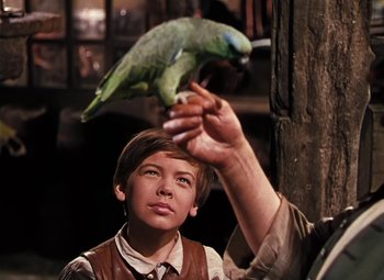 Movie still from “Treasure Island” (1950), directed by Byron Haskin – A young boy holding a parrot up to his head; Close Up shot, Over the shoulder angle