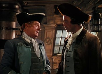 Movie still from “Treasure Island” (1950), directed by Byron Haskin – Two men in colonial garb talking to each other; Medium shot, Over the shoulder angle