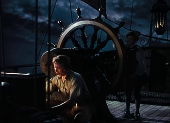 Movie still from “Treasure Island” (1950), directed by Byron Haskin – A man and a woman standing next to each other on a boat; Wide shot, High angle