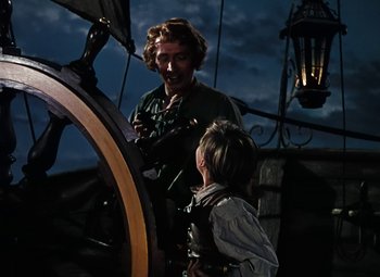 Movie still from “Treasure Island” (1950), directed by Byron Haskin – A woman and a child standing next to a ship wheel; Medium shot, High angle