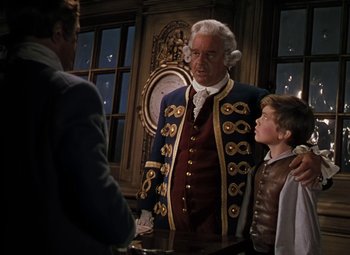 Movie still from “Treasure Island” (1950), directed by Byron Haskin – A man and two boys standing next to each other in front of a clock; Medium shot, Over the shoulder angle