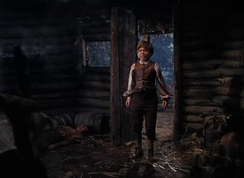 Movie still from “Treasure Island” (1950), directed by Byron Haskin – A man standing inside of a log cabin; Wide shot, High angle