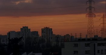 Movie still from “Trouble Every Day” (2001), directed by Claire Denis – A view of a city at sunset with power lines in the foreground; Extreme Wide shot, Low angle