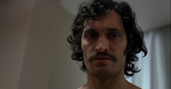 Movie still from “Trouble Every Day” (2001), directed by Claire Denis – A person with a beard and a mustache; Close Up shot, Low angle
