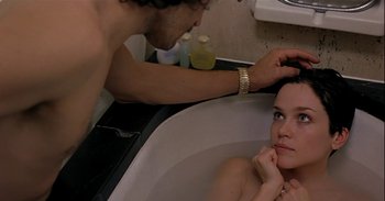 Movie still from “Trouble Every Day” (2001), directed by Claire Denis – A woman sitting in a bath tub with a man touching her hair; Close Up shot, High angle