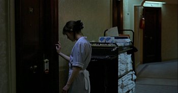 Movie still from “Trouble Every Day” (2001), directed by Claire Denis – A woman standing in front of a pile of papers; Medium shot, Over the shoulder angle