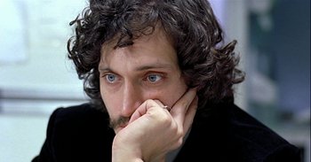 Movie still from “Trouble Every Day” (2001), directed by Claire Denis – A person wearing a suit and holding his hand to his face; Close Up shot, High angle