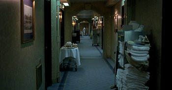 Movie still from “Trouble Every Day” (2001), directed by Claire Denis – A hotel hallway with tables and chairs in it; Wide shot, High angle