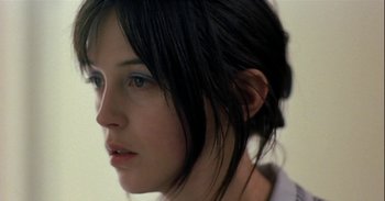 Movie still from “Trouble Every Day” (2001), directed by Claire Denis – A woman's face with long black hair; Close Up shot, Over the shoulder angle