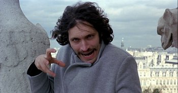 Movie still from “Trouble Every Day” (2001), directed by Claire Denis – A man with long curly hair is smiling and making a funny face; Close Up shot, Low angle