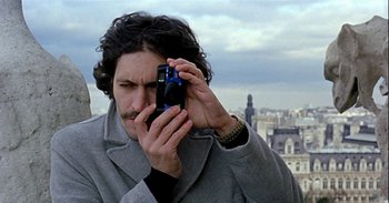 Movie still from “Trouble Every Day” (2001), directed by Claire Denis – A man taking a picture with a cell phone; Close Up shot, Low angle