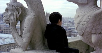 Movie still from “Trouble Every Day” (2001), directed by Claire Denis – A young boy sitting on top of a building looking out over the city; Medium shot, Over the shoulder angle