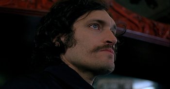 Movie still from “Trouble Every Day” (2001), directed by Claire Denis – A person with long hair and a mustache; Close Up shot, Low angle
