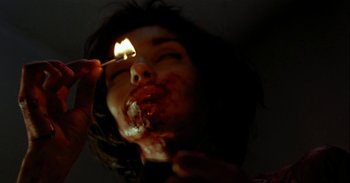 Movie still from “Trouble Every Day” (2001), directed by Claire Denis – A woman is holding a lit match in her mouth; Extreme Close Up shot, Low angle