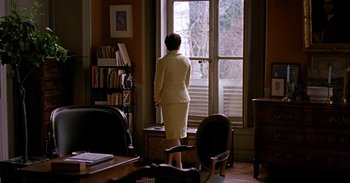 Movie still from “Trouble Every Day” (2001), directed by Claire Denis – A woman standing in front of a window looking outside; Wide shot, Over the shoulder angle