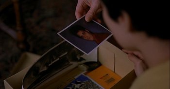 Movie still from “Trouble Every Day” (2001), directed by Claire Denis – A person looking at a picture of a person; Extreme Close Up shot, High angle