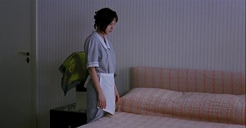 Movie still from “Trouble Every Day” (2001), directed by Claire Denis – A woman standing on top of a bed in a room; Medium shot, High angle