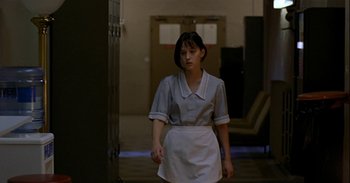 Movie still from “Trouble Every Day” (2001), directed by Claire Denis – A woman in a maid uniform walking down a hall way; Medium shot, Low angle