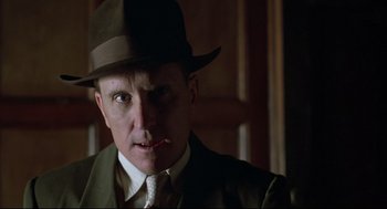 Movie still from “True Confessions” (1981), directed by Ulu Grosbard – A man wearing a hat and a suit smoking a cigarette; Close Up shot, Low angle