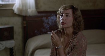 Movie still from “True Confessions” (1981), directed by Ulu Grosbard – A woman is smoking a cigarette in a room; Close Up shot, Over the shoulder angle