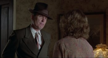 Movie still from “True Confessions” (1981), directed by Ulu Grosbard – A man wearing a suit and a hat talking to a woman; Close Up shot, Over the shoulder angle