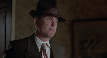 Movie still from “True Confessions” (1981), directed by Ulu Grosbard – A man wearing a suit and a hat in a room; Close Up shot, Low angle