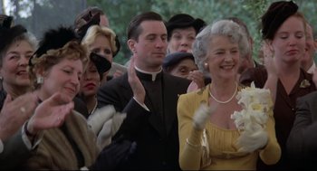 Movie still from “True Confessions” (1981), directed by Ulu Grosbard – A group of people standing in front of each other; Medium shot, Low angle