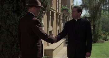 Movie still from “True Confessions” (1981), directed by Ulu Grosbard – Two men in suits and hats shaking hands outside; Medium shot, Low angle