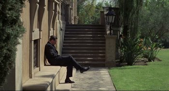 Movie still from “True Confessions” (1981), directed by Ulu Grosbard – A man sitting on the steps of a building; Wide shot, High angle