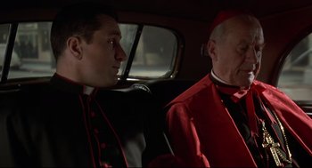 Movie still from “True Confessions” (1981), directed by Ulu Grosbard – Two men sitting in the back seat of a car; Medium shot, High angle