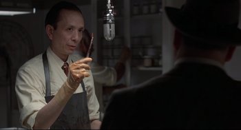 Movie still from “True Confessions” (1981), directed by Ulu Grosbard – A man holding a paintbrush in front of a microphone; Close Up shot, Low angle