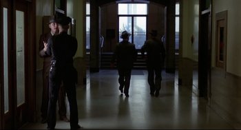 Movie still from “True Confessions” (1981), directed by Ulu Grosbard – A group of men walking down a hall way; Wide shot, Low angle