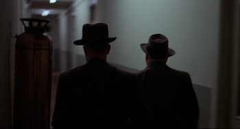 Movie still from “True Confessions” (1981), directed by Ulu Grosbard – A couple of men wearing hats and standing next to each other; Medium shot, Low angle