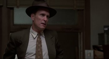 Movie still from “True Confessions” (1981), directed by Ulu Grosbard – A man wearing a suit and tie and a hat; Close Up shot, Low angle