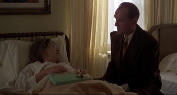 Movie still from “True Confessions” (1981), directed by Ulu Grosbard – An older man sitting next to an older woman in a hospital bed; Medium shot, Over the shoulder angle